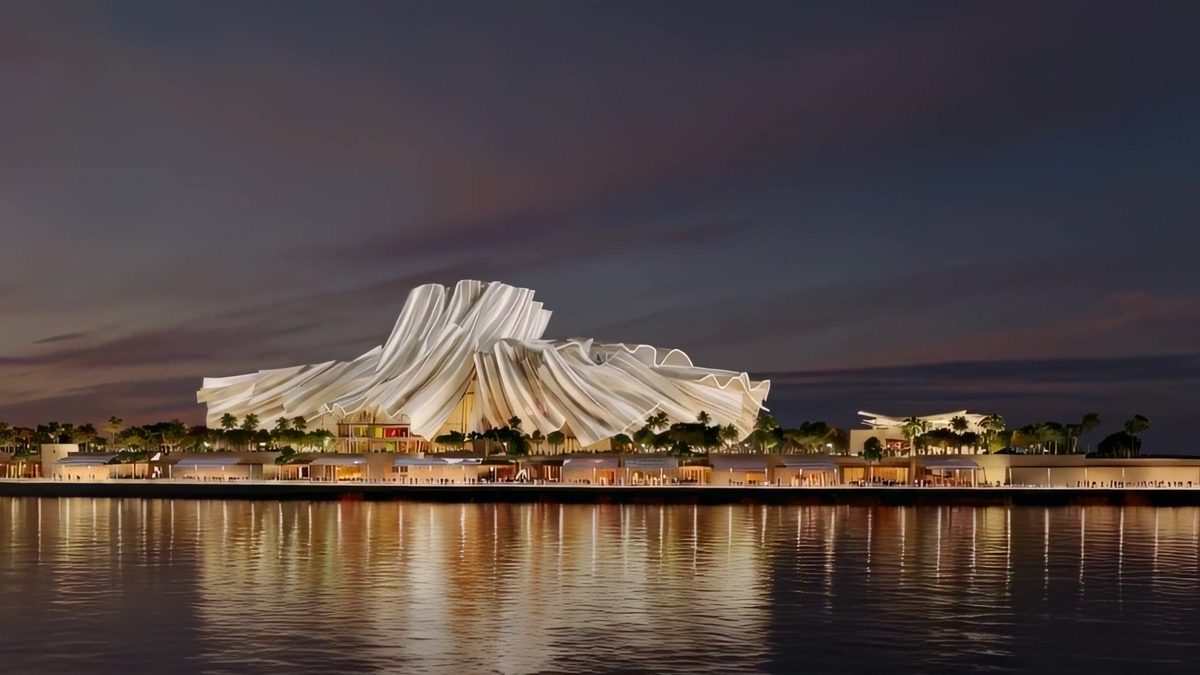Dar Al Funoon at dusk: a sculpted, fabric-like facade lit above the water