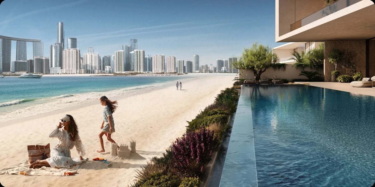 A mother and daughter building a sandcastle on the beach beside a pool, the skyline across the water
