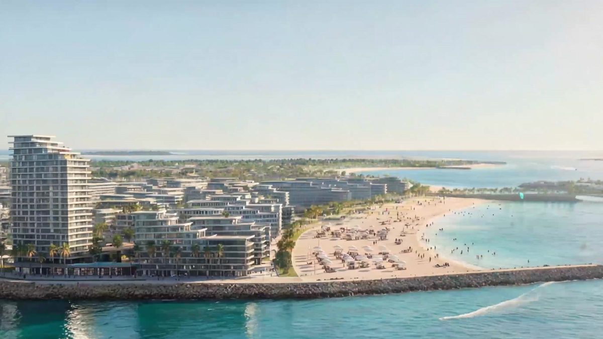 The Marsa Al Saadiyat shore from the air: residential buildings above a wide beach, a breakwater and open turquoise water