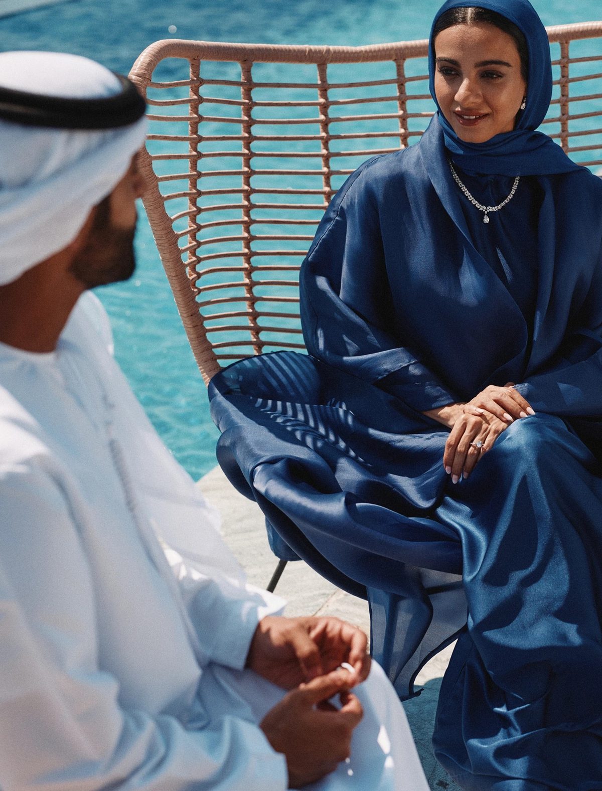 An Emirati couple in conversation beside a pool
