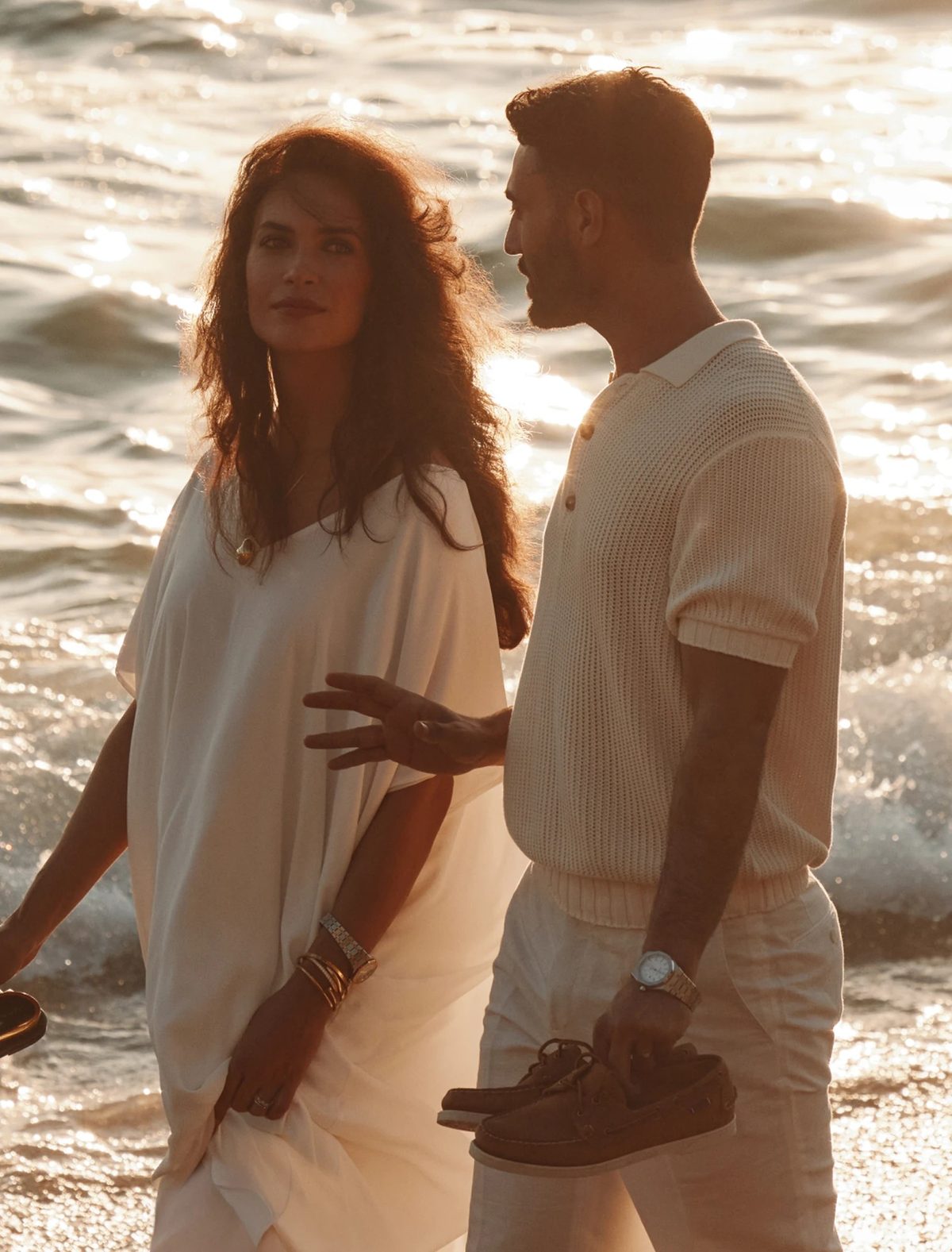 A couple walking in the shallows at golden hour