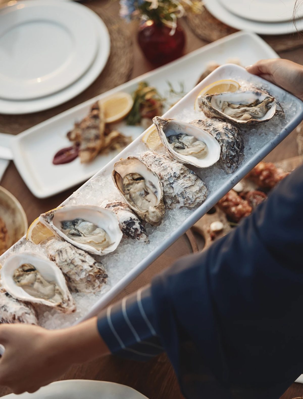 A platter of oysters served at a table by the water