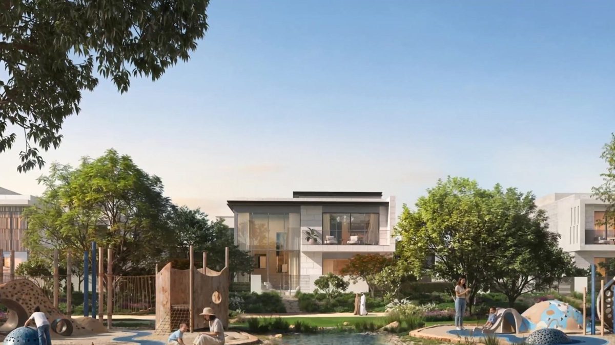 A neighbourhood park with a shallow water-play channel and timber play structures, villas behind the trees