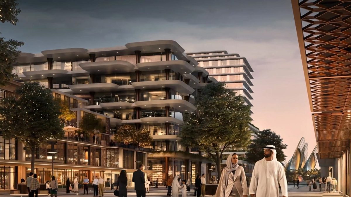 A residential building with rounded balconies above a lit colonnade, people walking the evening promenade