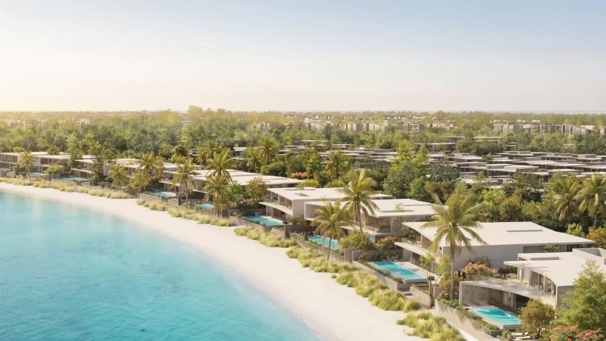 Villas with private pools along a white-sand beach, seen from the air